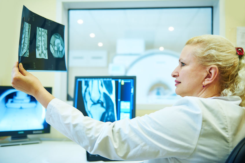 Computed tomography scanner test. female radiologist woman examining x-ray image on digital display.